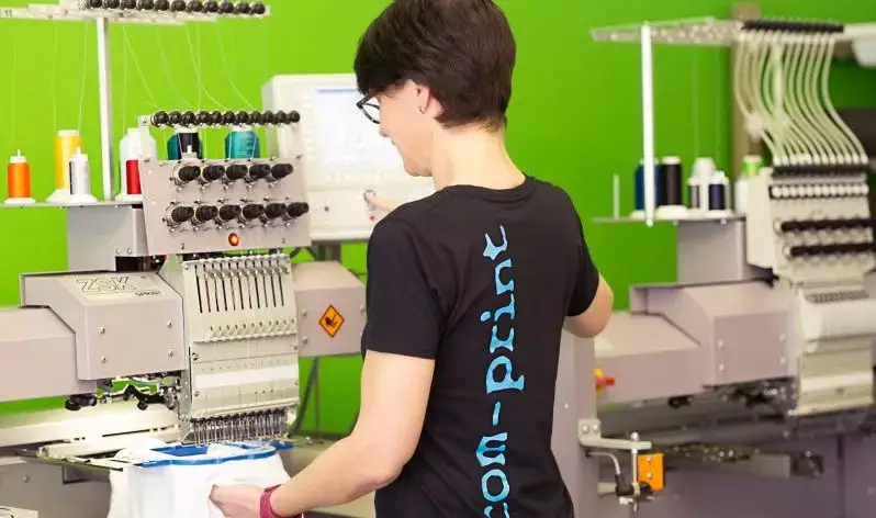 Eine Mitarbeiterin arbeitet an einer Stickmaschine.